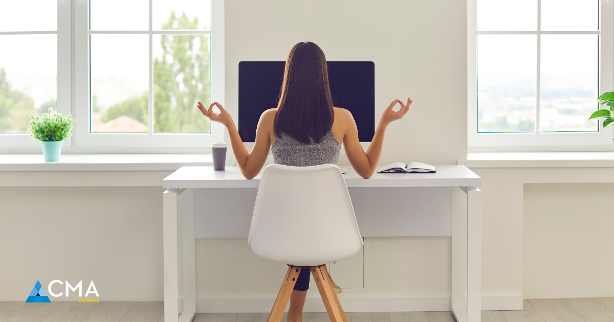 A woman sitting at a desk practicing mindfulness, symbolizing empowerment and work-life balance for women leaders.